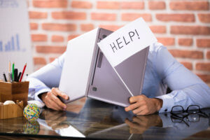 A man with a laptop over his head and a help sign